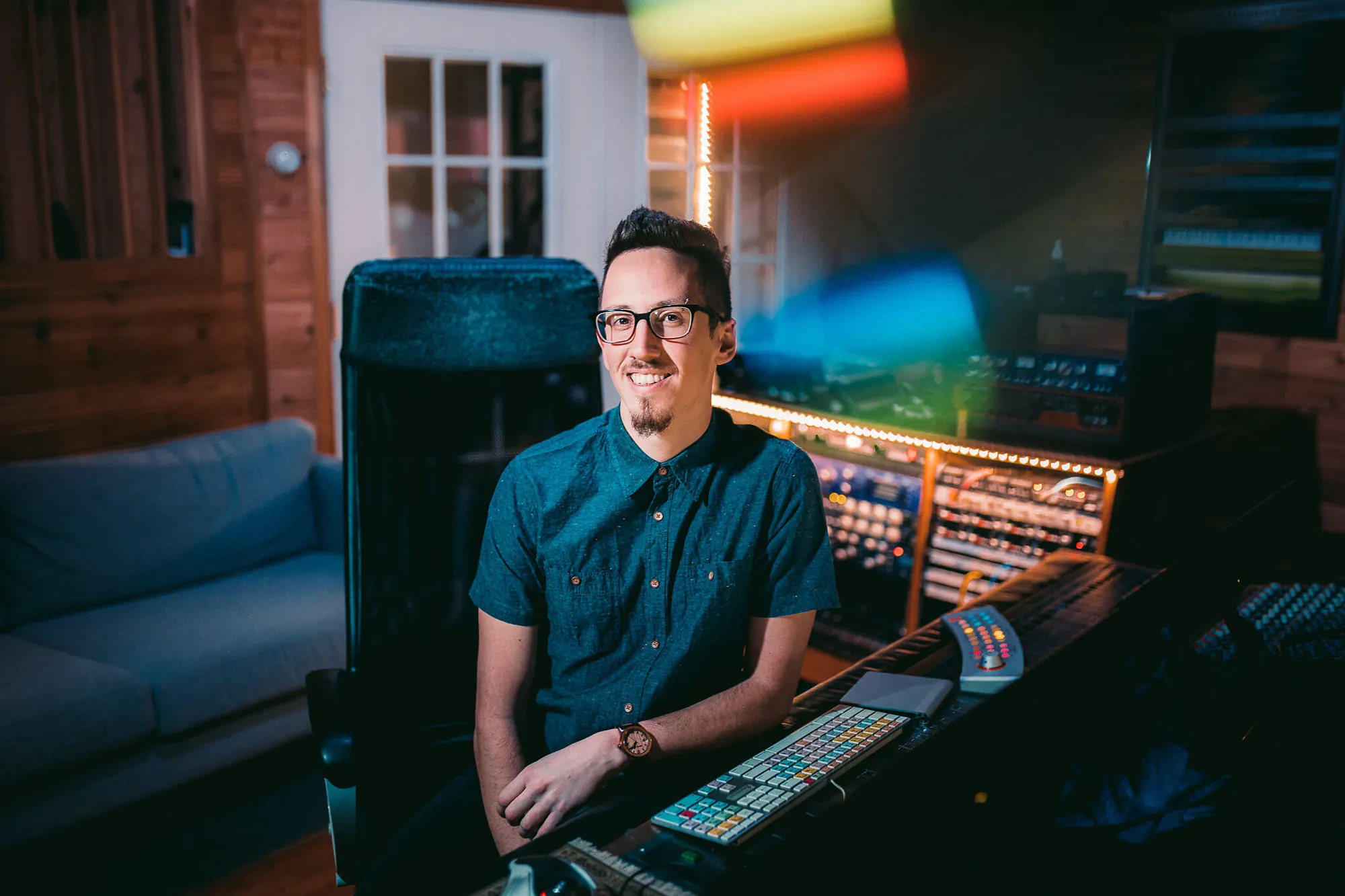 Nate Lanzino smiling at a mixing console in a wood-panelled control room